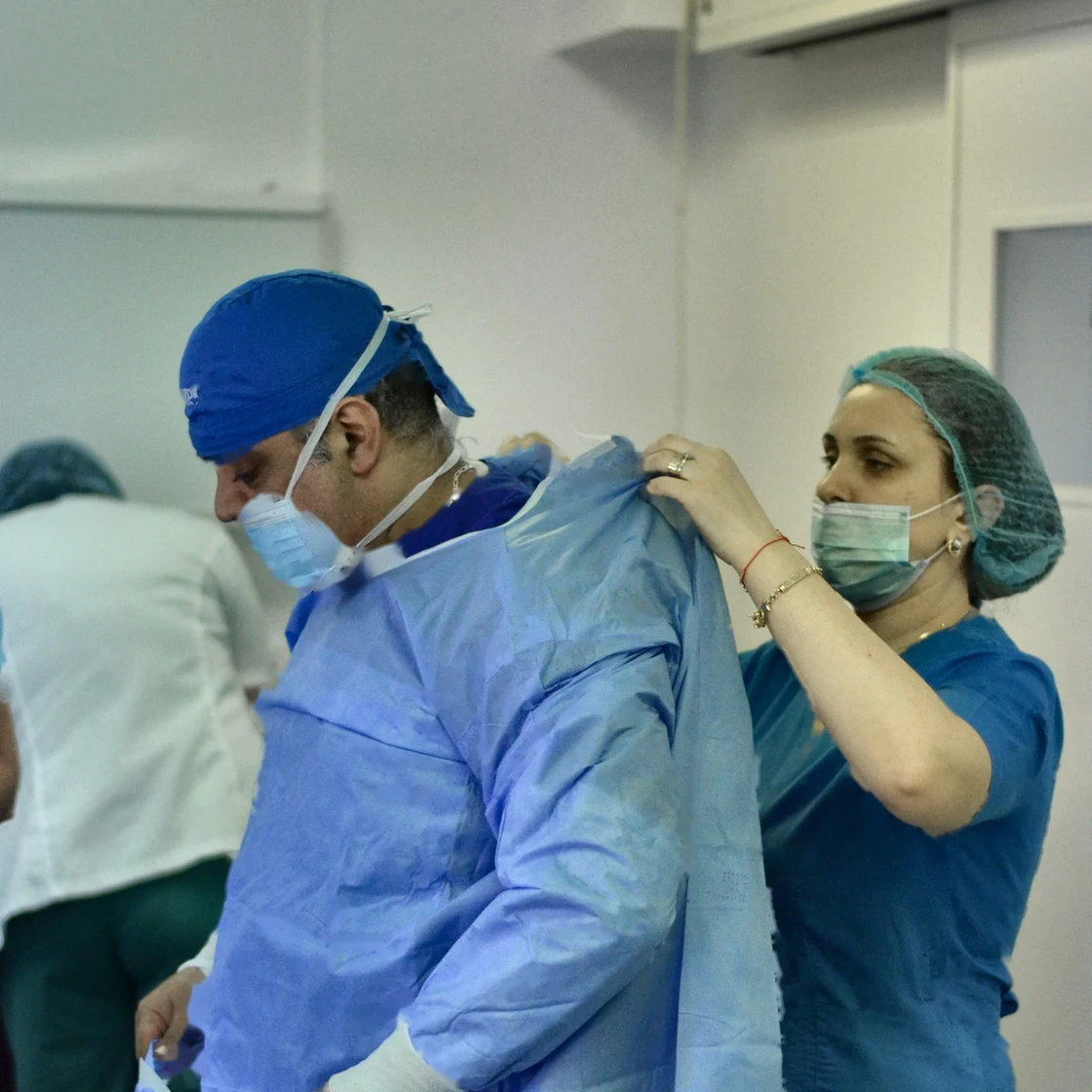 Dr. Rachad se îmbracă în halat steril, cu ajutorul asistentei