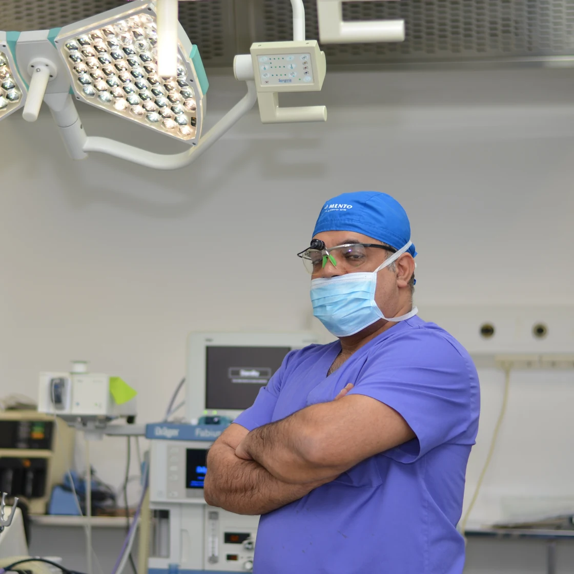 Dr. Rachad, în ținută de operație, cu brațele încrucișate, în sala de operație