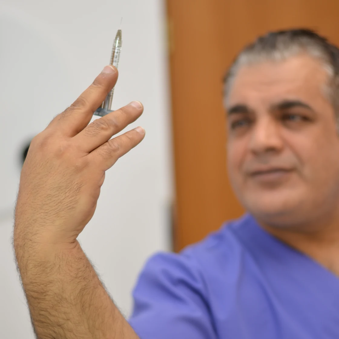Dr. Rachad, zâmbind, ținând în mână un bisturiu, în clinica Art Estetica