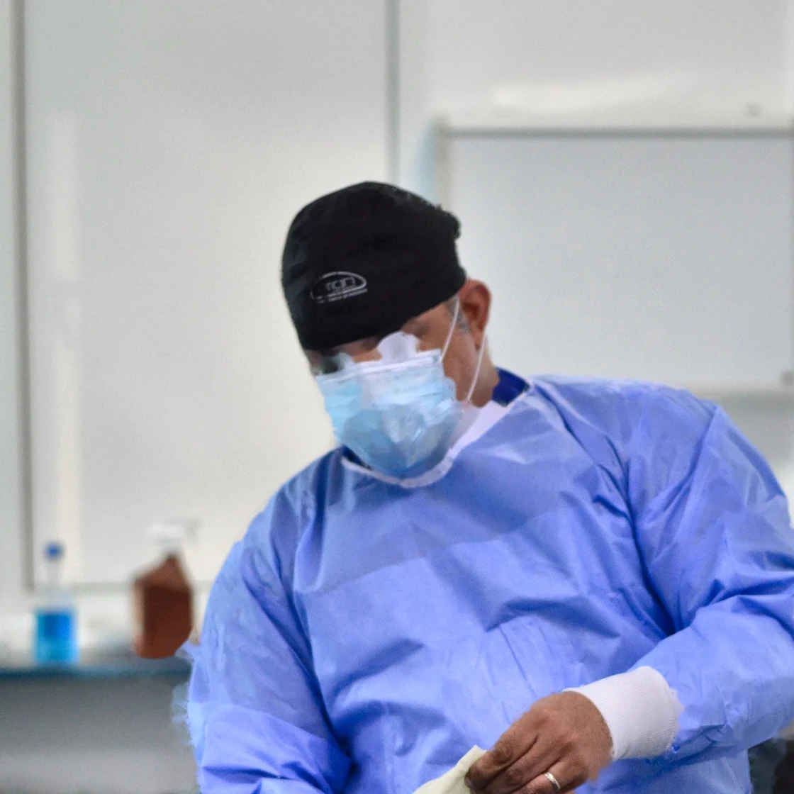 Dr. Rachad își pune mănușile chirurgicale, în sala de operație, înainte de liposucție
