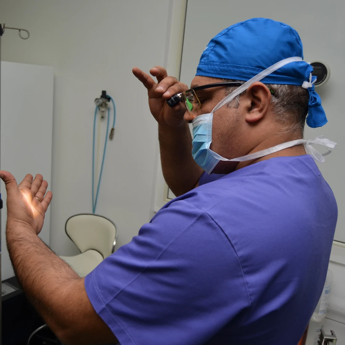 Dr. Rachad, în ținută de operație, își aranjează ochelarii de protecție înainte de liposucția Vaser